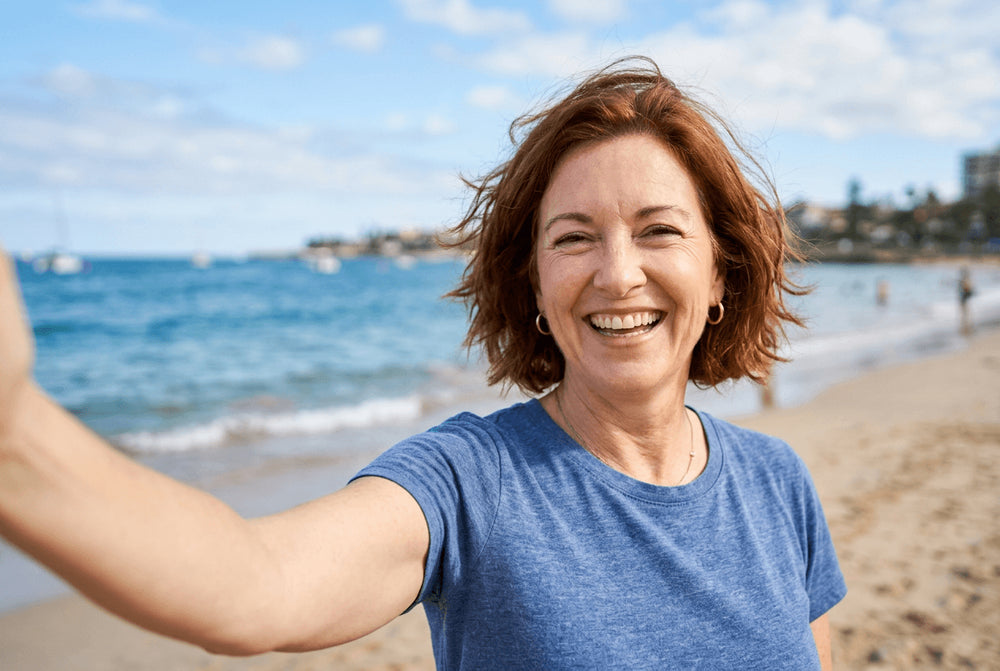 Flowell: Woman taking a selfie on a beach with ocean and skyline in the background