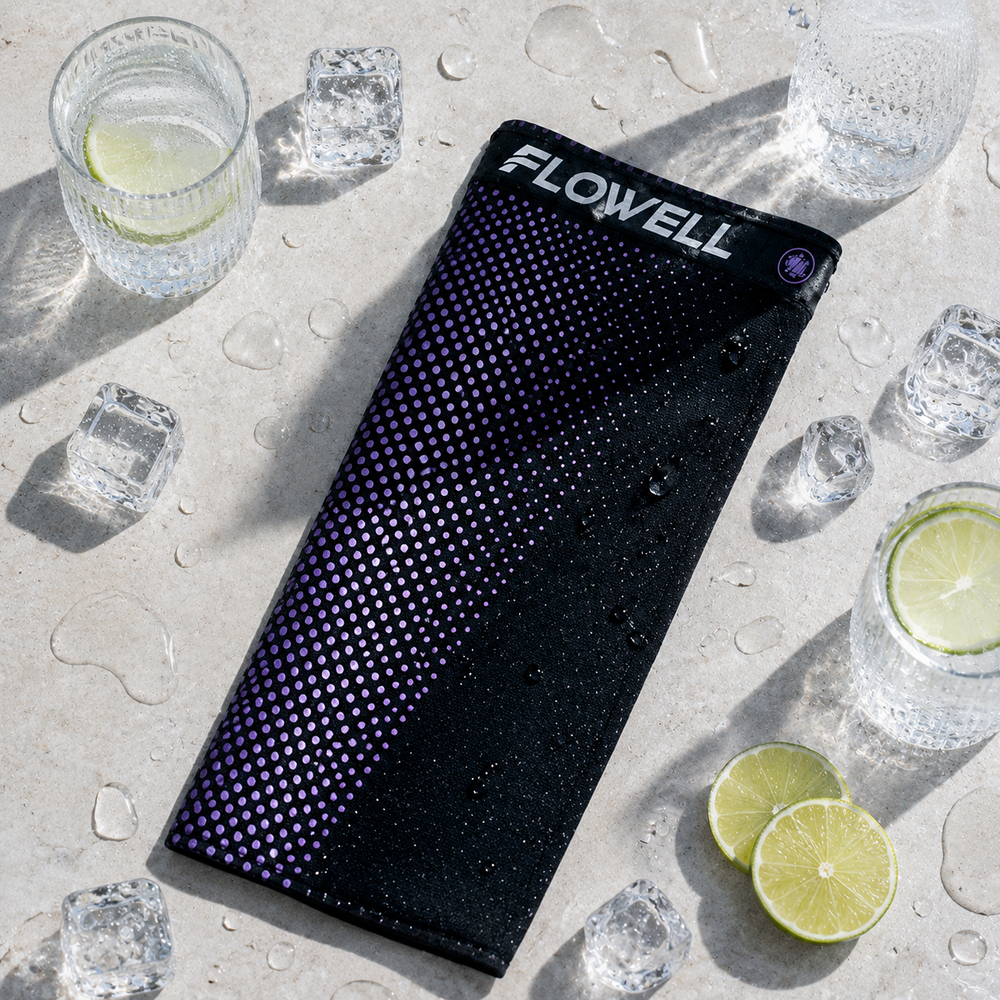 Flowell: Black cooling towel with 'Flowell' branding on a concrete surface with drinks and lime slices.