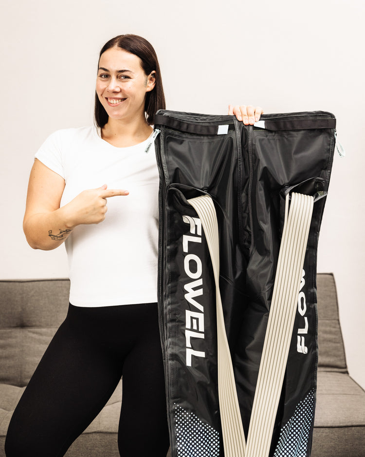 Flowell - Woman holding her Flowell Home Deluxe Pants up to her shoulders and pointing at them with a smile