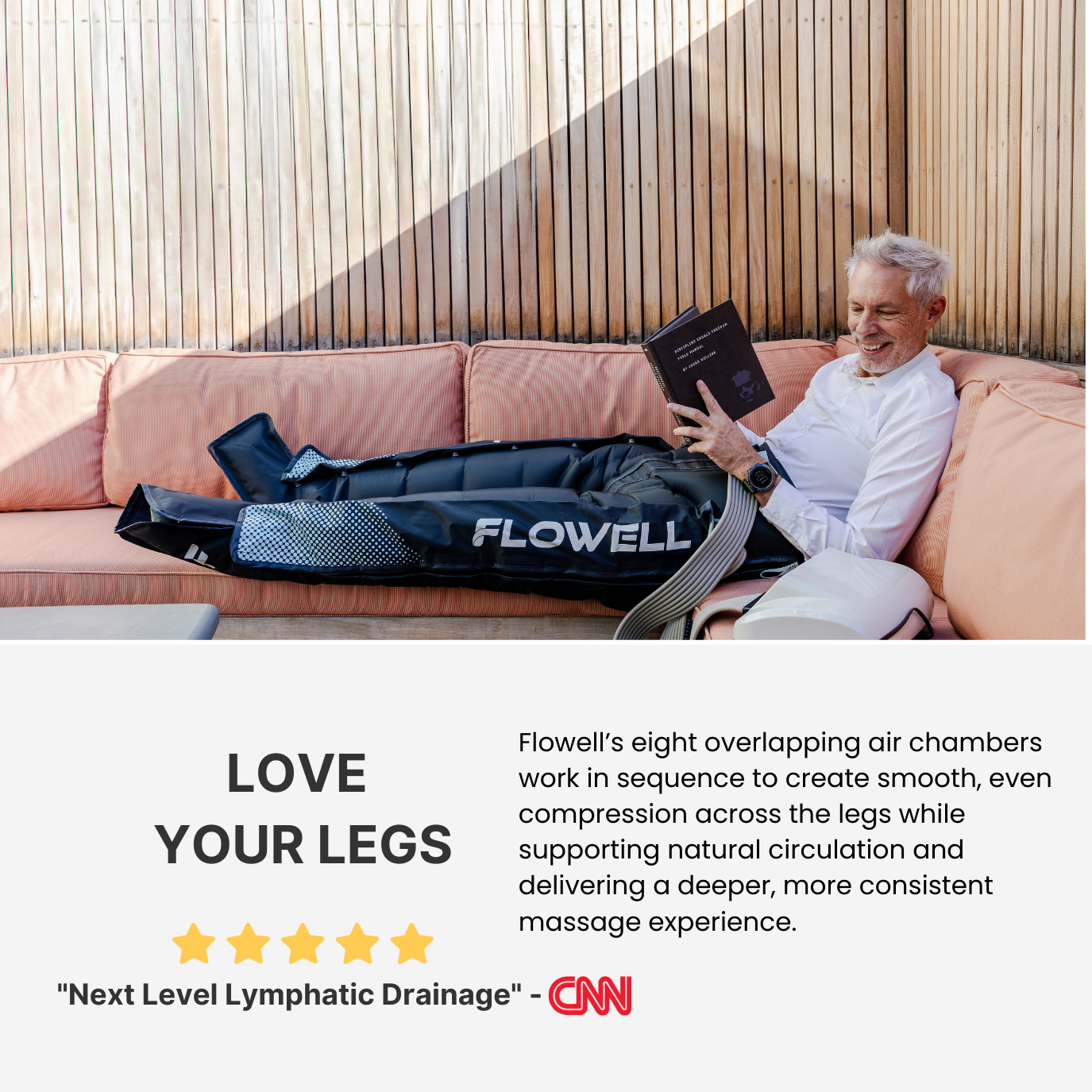 Man sitting on a couch with Flowell leg compression device, reading a book.