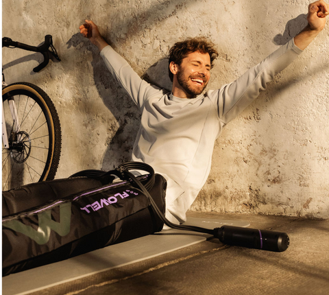 Flowell - Man sitting on the floor next to a bike, wearing his Flowell Mobile Boots set and stretching his arms out