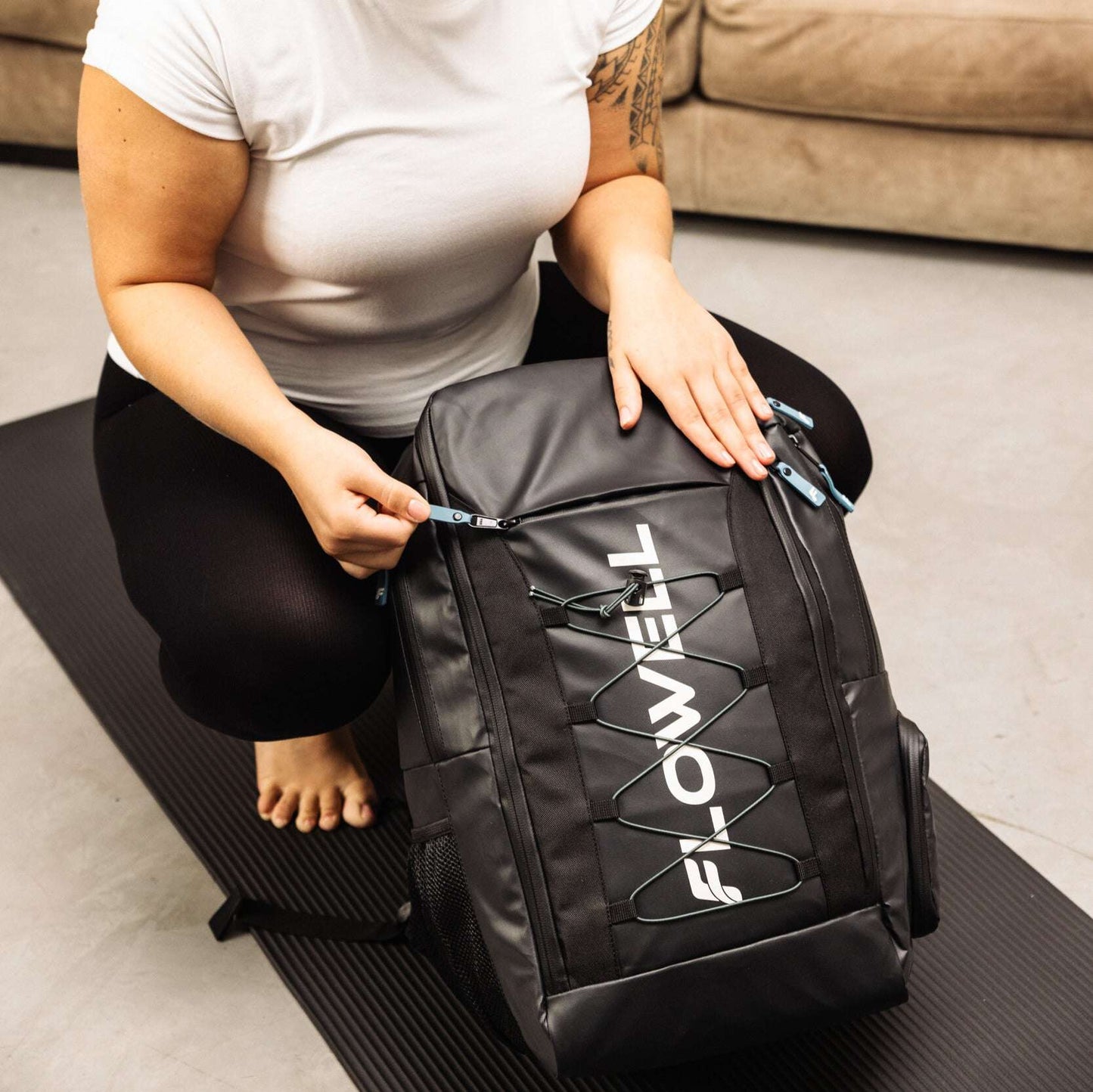 Flowell Pro Gear Backpack - Close up shot of woman zipping up her black and light blue Pro Gear Backpack