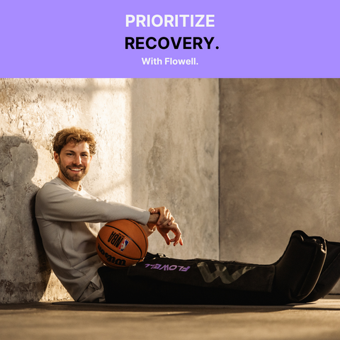 Flowell Sport Mobile Boots Set - Man sitting on the floor using his Flowell Sport Mobile Boots Set in black and purple while holding a basketball. Prioritize recovery with Flowell