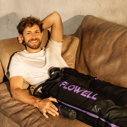 Flowell Sport Mobile Pants Set - Man laying on couch wearing Flowell Sport Mobile Pants Set in black and purple and holding it's portable control unit. The new standard with Flowell