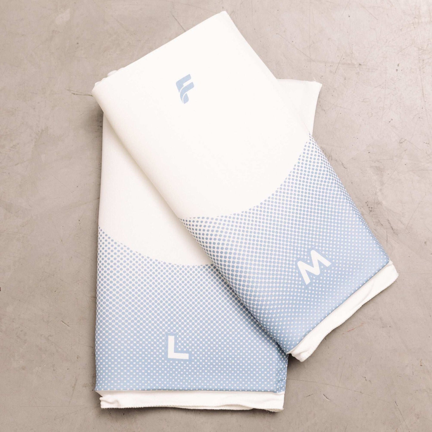 Flowell Thermosleeve - Flowell white and light blue thermosleeves in Medium and Large arranged on a beige background