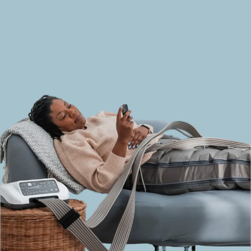 Flowell - Woman laying on a couch wearing Flowell ome Deluxe Pants and holding the device remote in her hand